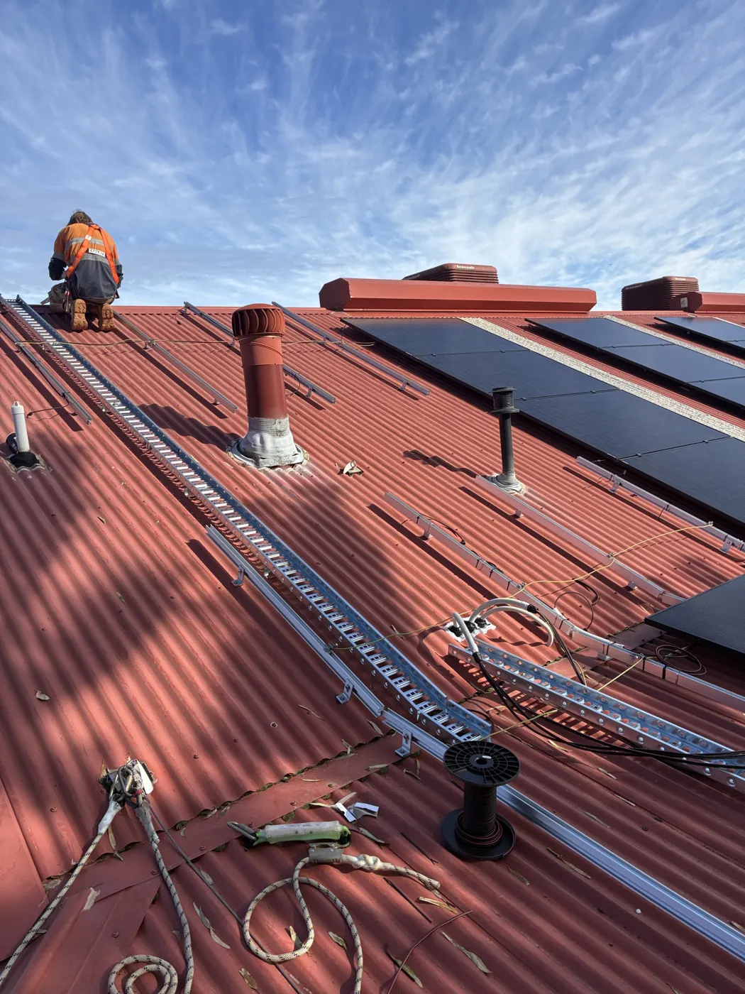 Installer fitting solar panels on the school roof