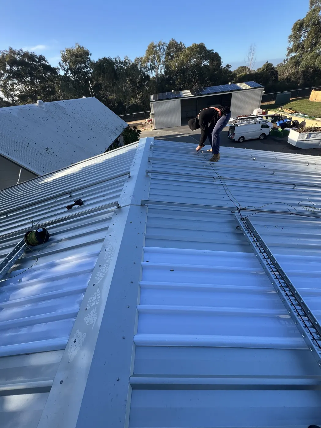 Installer laying out solar racking on the roof at Karrakatta