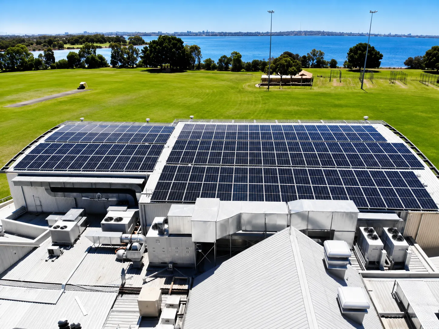Aerial view of a large rooftop solar system installed by Infinity on a community facility beside the river
