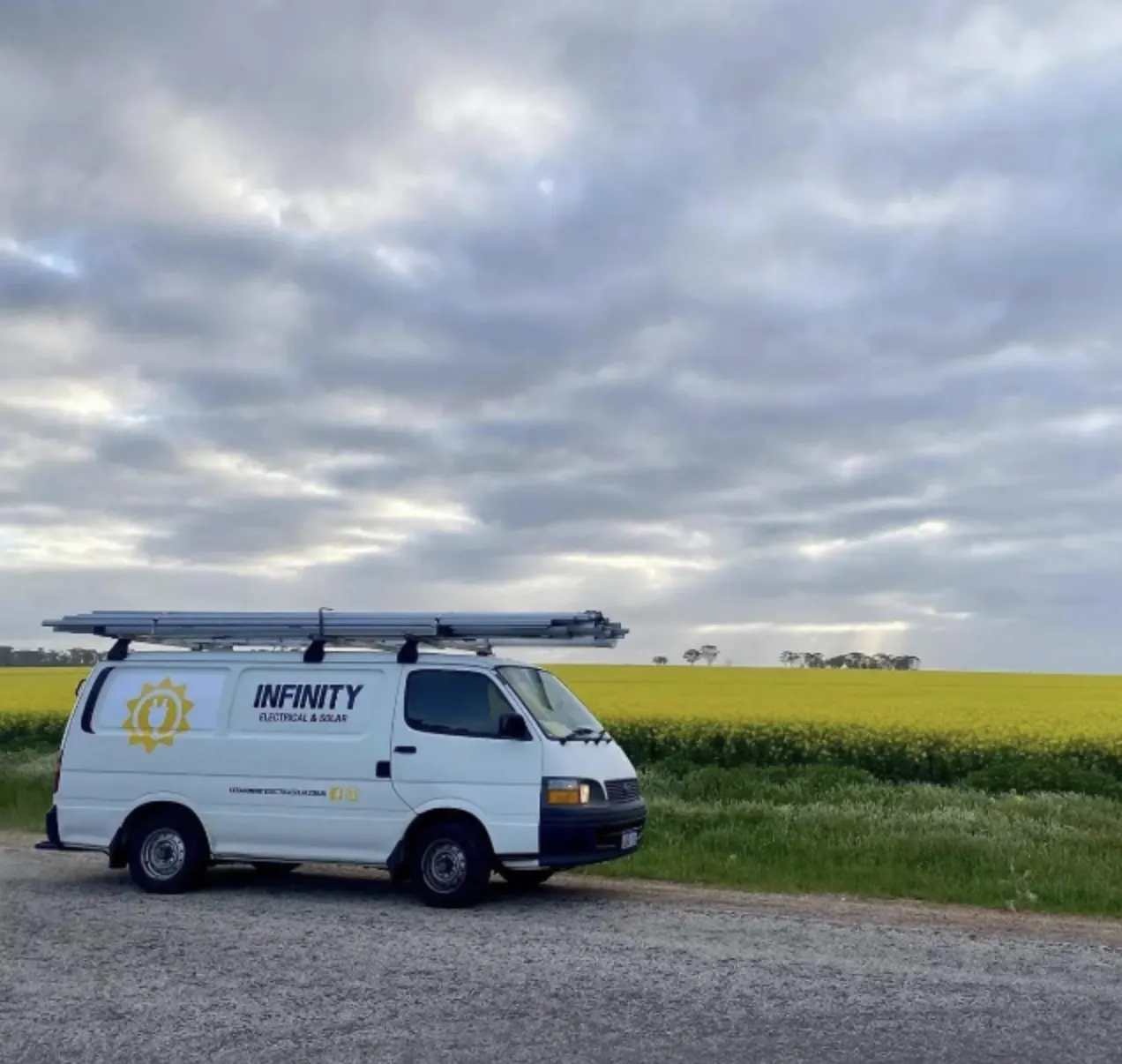 Infinity Electrical & Solar van parked beside a canola field